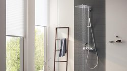 Ein modernes Badezimmer mit einer eleganten Dusche, die sanft Wasser sprüht, und großen Fenstern, die Tageslicht hereinlassen.